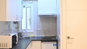 A kitchen with a microwave, sink, and cabinets. - Homenfun Barcelona Les Corts (Barcelona)