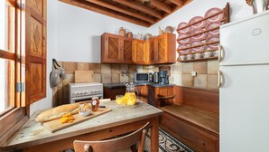 A kitchen with wooden cabinets, a stove, a microwave, and a refrigerator. - Traditional 17th Century Lindos Captains House

 (Lindos)