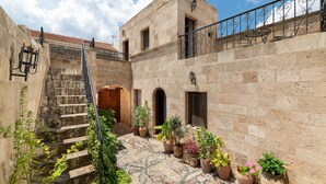 A courtyard with stone walls, a staircase, and potted plants. - Traditional 17th Century Lindos Captains House

 (Lindos)