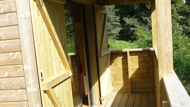 A wooden deck with a door leading to an interior space.