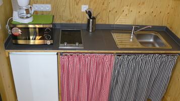 Een kleine keuken met een koffiezetapparaat, magnetron, broodrooster en spoelbak.