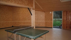 A ping pong table in a room with wooden walls and a tiled floor.