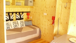 A cozy room with a bed, a small table, and a shelf with storage boxes.