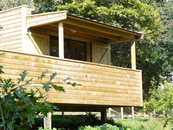 A wooden cabin with a balcony, surrounded by greenery. - Cabin fully equipped, comfortable, quiet, in the Bay of Mont Saint-Michel (Saint-Martin-Des-Champs)