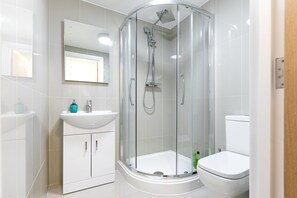 A modern bathroom with a glass-enclosed shower, a white sink, and a toilet. - KVM - City Apartments (Peterborough)
