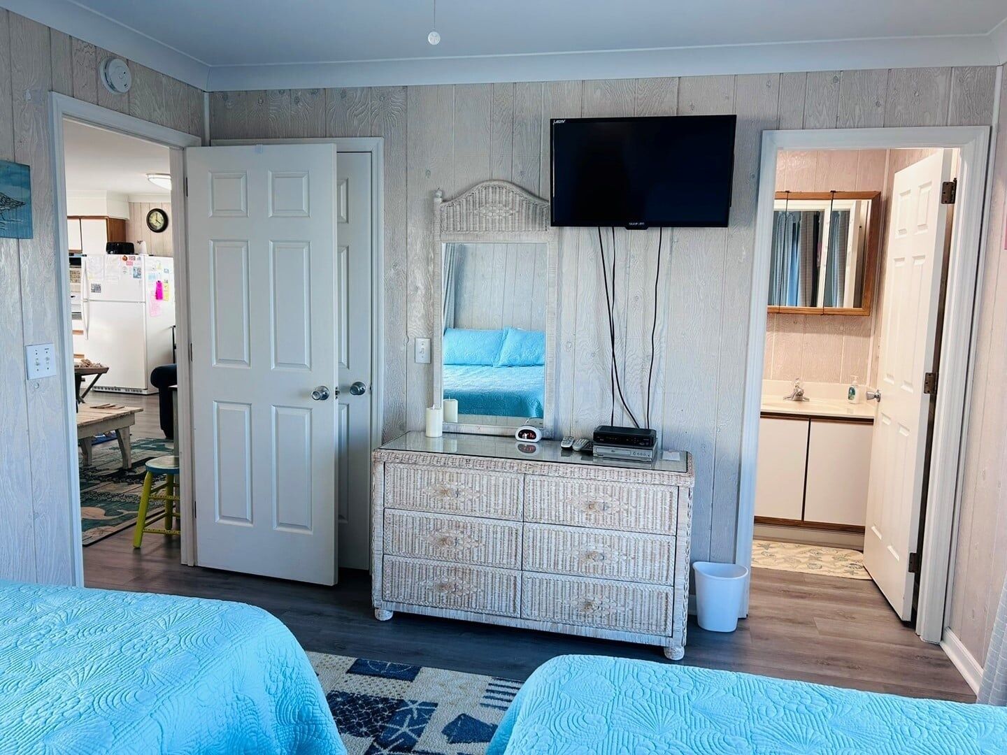 A bedroom with a bed, dresser, TV, and a bathroom visible through an open door.