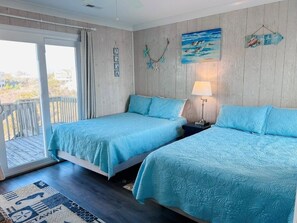A bedroom with two beds, a window, a door, and a view of the outdoors. - Sea It All 2 Bedroom Home by RedAwning (Supply)
