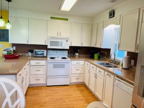 A kitchen with white cabinets, a microwave, a stove, and a dishwasher. - Beach Bells 4 Bedroom Home by RedAwning (Supply)