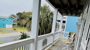A wooden deck with white railings and yellow cushioned chairs. - Beach Bells 4 Bedroom Home by RedAwning (Supply)