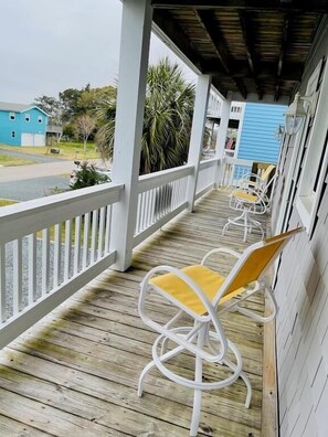A wooden deck with white railings and yellow cushioned chairs. - Beach Bells 4 Bedroom Home by RedAwning (Supply)