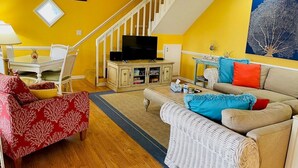 A living room with a staircase, a television, a dining table, and a sofa.