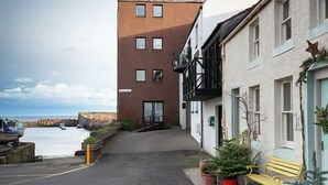 A narrow street with a building on the left and a bench on the right. - Unique 2 Bedroom Harbour Front Apartment. License No. EL00051F.     (Dunbar)