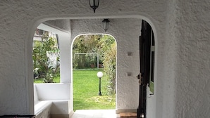 A covered patio area with a foosball table, a sofa, and a view of a garden through an archway. - Detached villa on 2 levels, newly renovated and super-equipped (San Felice Circeo)