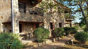 A stone building with a balcony, surrounded by well-maintained greenery and a gravel pathway. - Stone bastide in a peaceful, closed park 700 m from the beach  (Porto-Vecchio)