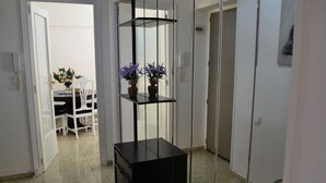 Un pasillo con un estante negro, una puerta blanca y un comedor al fondo.