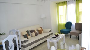 Una sala de estar con sofá, sillas, una mesa de centro y una lámpara.