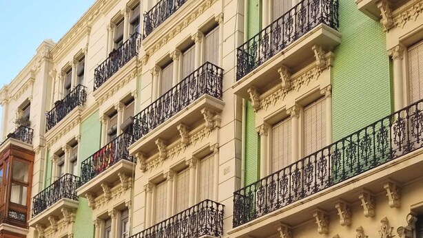 Un edificio con balcones ornamentales y un restaurante llamado "Family-Rou Restaurant" con mesas al aire libre.