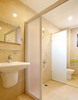 Un baño moderno con cabina de ducha de vidrio, lavamanos y retrete.