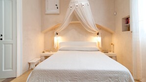 Un dormitorio con cama con dosel, lámparas de noche, una mesita de noche pequeña y un mueble auxiliar.