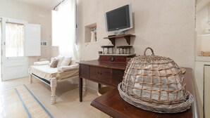 Un dormitorio con cama, escritorio, televisor y cesta de mimbre.