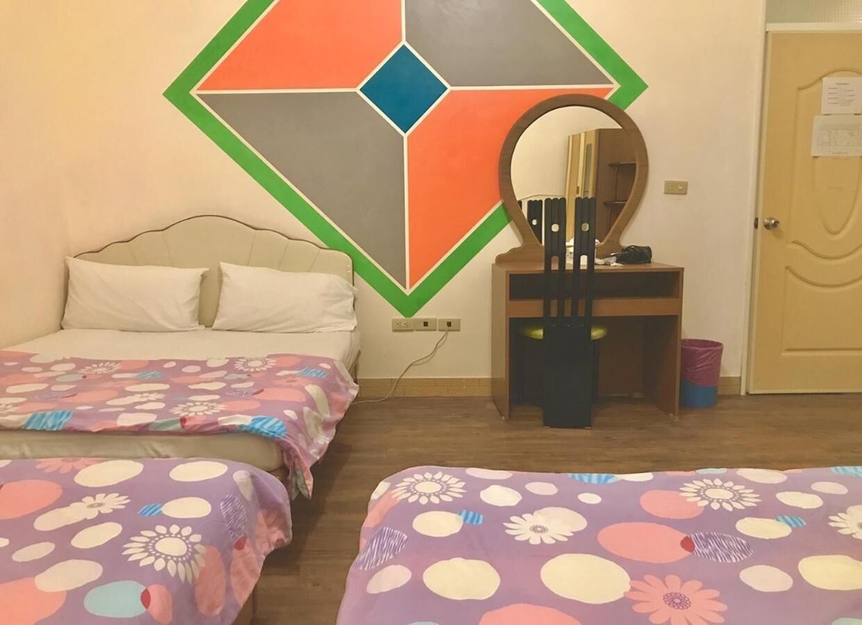 A room with two beds, a mirror, a small table, and a door.
