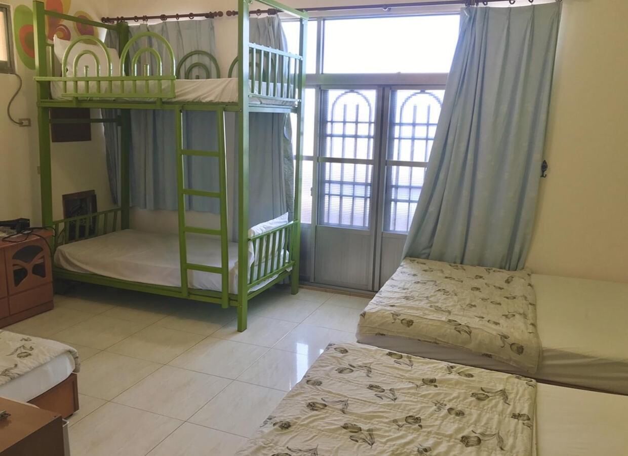 A room with bunk beds, a sofa, and a small table.