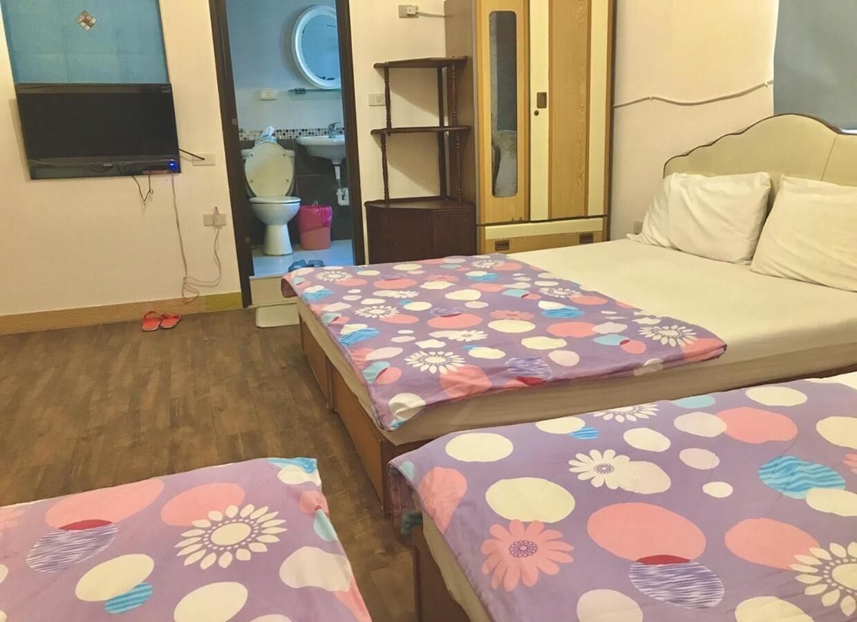 A bedroom with two single beds, a wooden wardrobe, a mirror, and a bathroom visible through an open door.