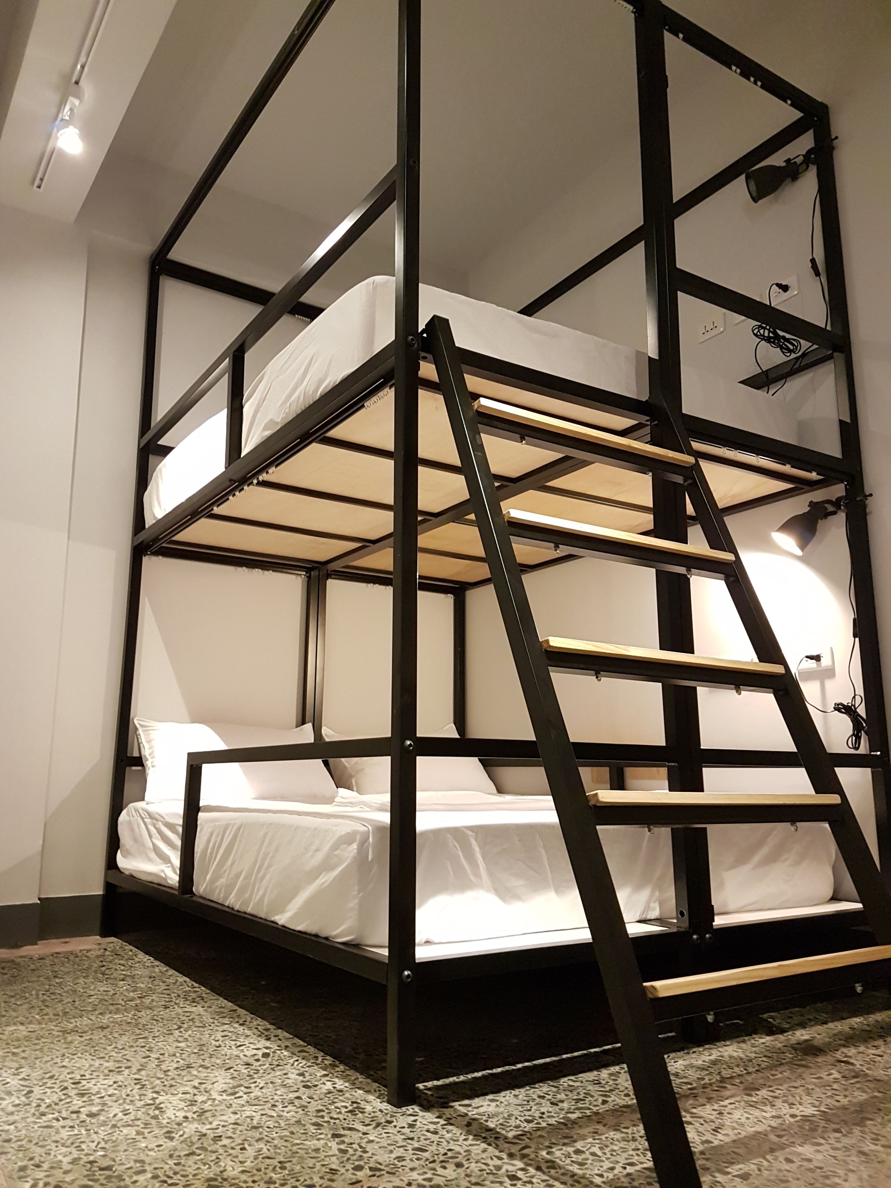 A bunk bed with a ladder, white bedding, and a speckled floor.