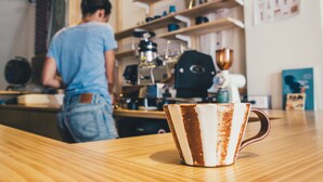 A rustic wooden table with a coffee cup in the foreground. - World Inn - Hostel (Hualien City)