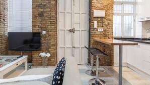 Un espace de vie compact comprenant un coin cuisine, un canapé, un téléviseur et une porte avec une fenêtre.