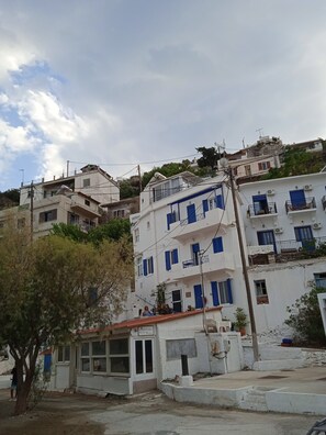 Un immeuble à plusieurs étages doté de balcons, un petit magasin au rez-de-chaussée et un ciel dégagé.