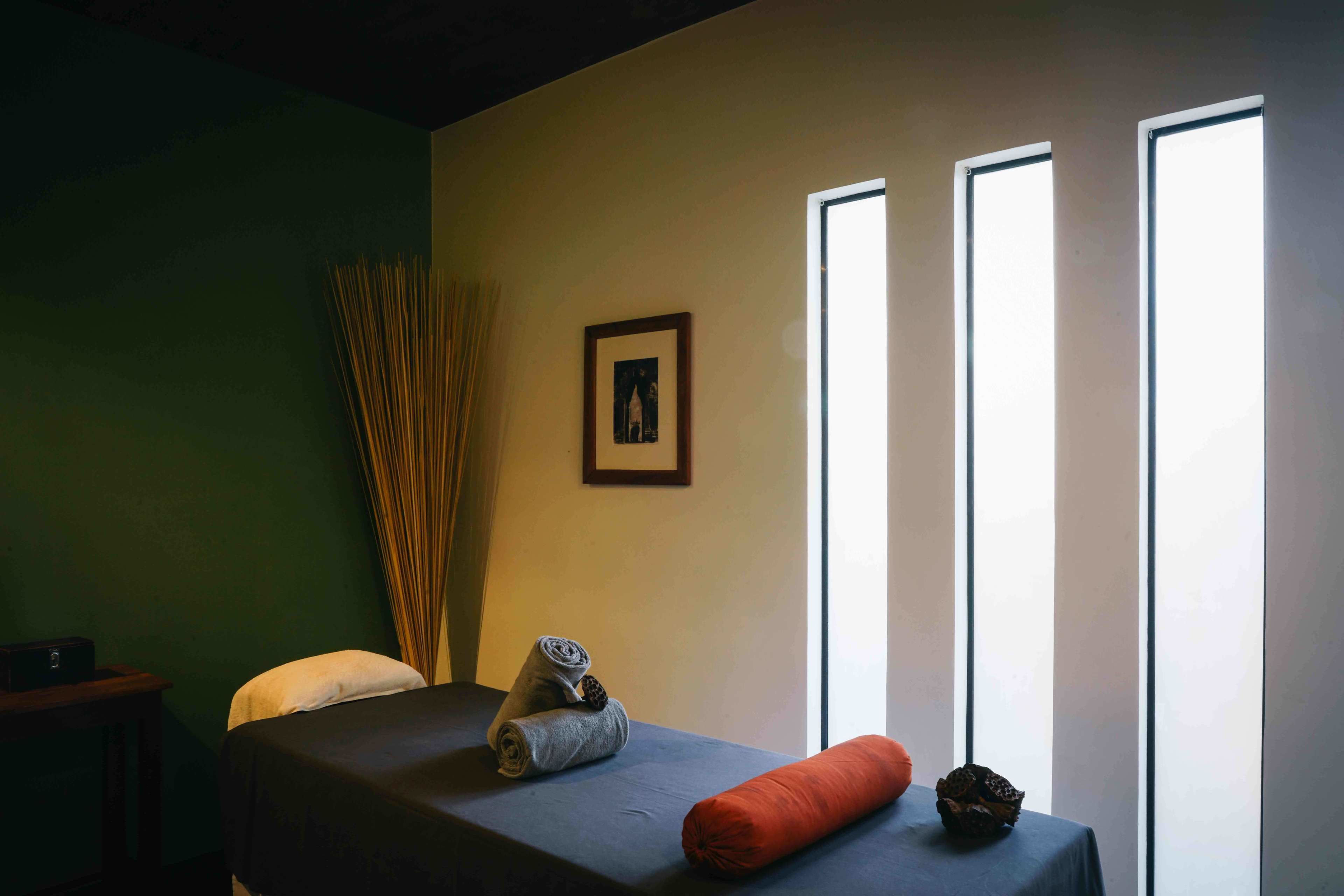 A room with a bed, a small table, a picture on the wall, and a window.