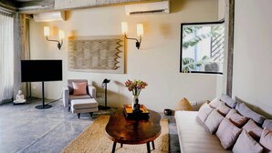 A living room with a flat-screen TV, a sofa, a coffee table, wall-mounted lights, and a ceiling fan. - Urban Residences - Siem Reap (Siem Reap)