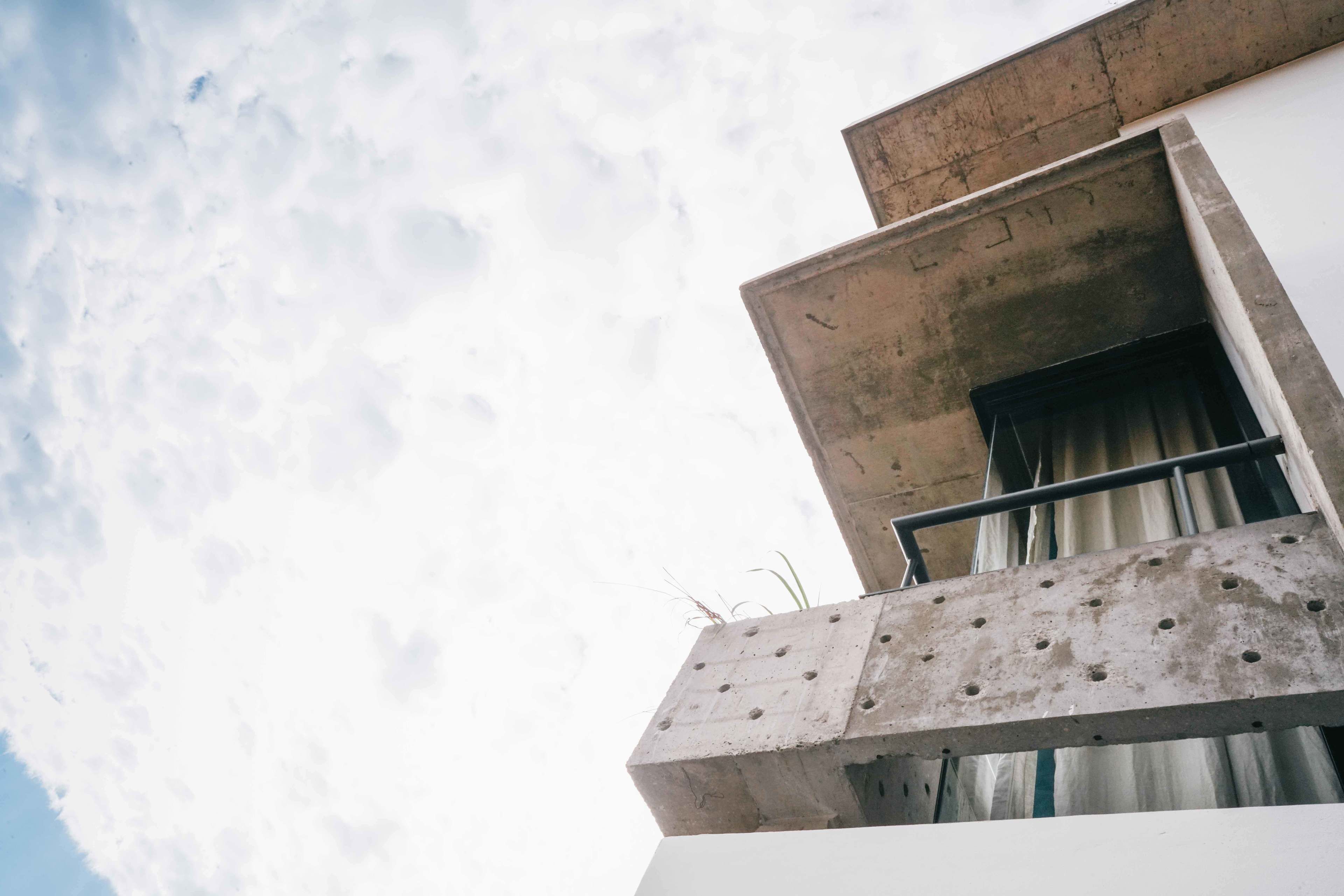 Um edifício de concreto com varanda e janela.