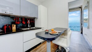 A modern kitchen with a dining area, a view of the sea, and a balcony.