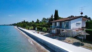 A seaside property with a balcony overlooking the sea, a swimming pool, and a well-maintained garden.