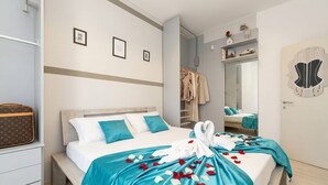 A hotel room with a bed, a bench, a suitcase, a wardrobe, and a mirror.