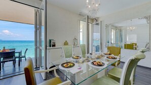 A dining area with a glass table, chairs, and a view of the ocean.