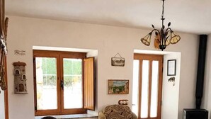 A living room with a sofa, a patterned armchair, a wooden coffee table, a fireplace, and a chandelier. - Galician Stone Cottage for 2 people   (A Coruña)