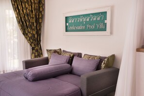 A bed with a headboard, a wall-mounted sign, and a window with curtains.