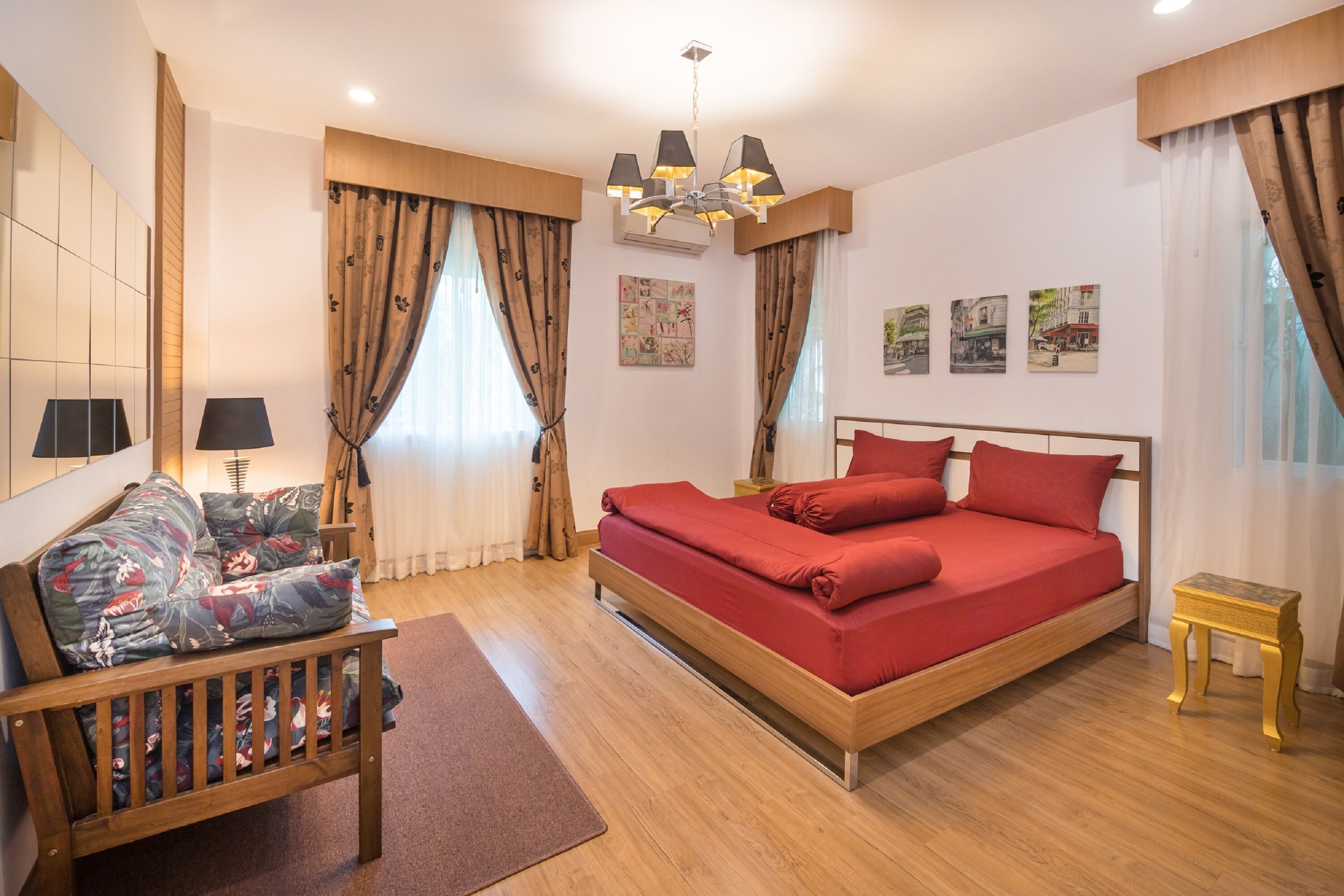Un dormitorio con cama, una silla, una mesita y obras de arte en las paredes.