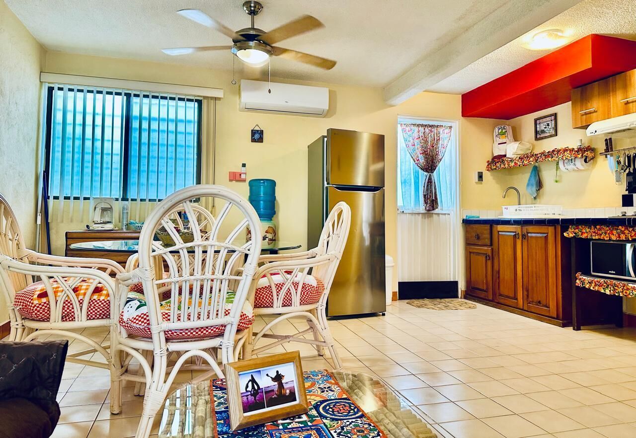 A dining area with wicker chairs, a table, and a ceiling fan.