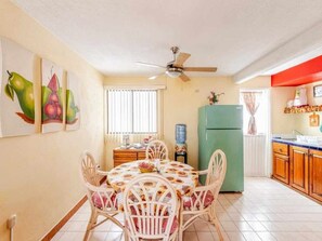 A dining area with a table and chairs, a ceiling fan, a refrigerator, and a kitchen counter.