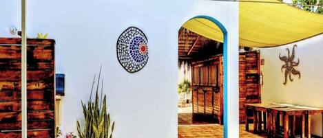 Un espacio al aire libre cubierto con una estructura de madera, un mosaico circular y una planta de cactus.