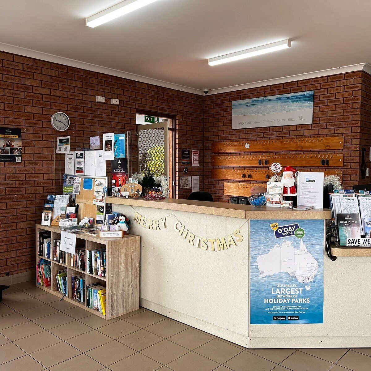 A reception desk with a 'Merry Christmas' sign, a clock, and a map of holiday parks.