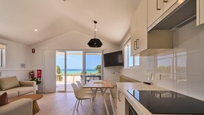 A modern kitchen with a large island, a dining area with a view, and a living space with a sofa and coffee table.
