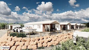 A holiday park with mobile homes, a boat, and a rocky landscape.