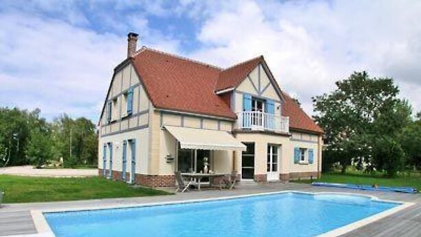 Ein zweistöckiges Haus mit Swimmingpool im Garten.