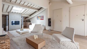 A modern living room with a high ceiling, a flat-screen TV mounted on the wall, a wooden coffee table, and a fluffy rug. - Penthouse Hilife Panoramic Terrace (Florence)