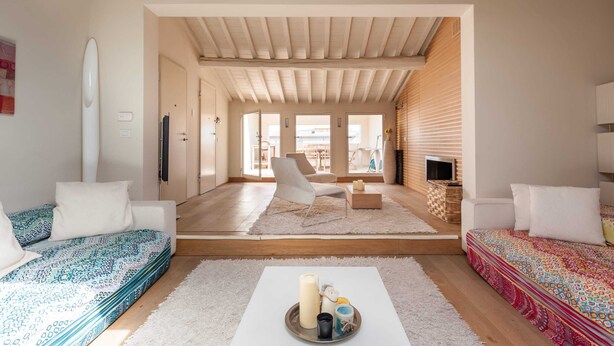 A spacious living room with a high ceiling, a sofa set, a coffee table with candles, and a view through an open door to a balcony. - Penthouse Hilife Panoramic Terrace (Florence)